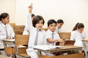 Glückliches indisches Schulkind hebt die Hand